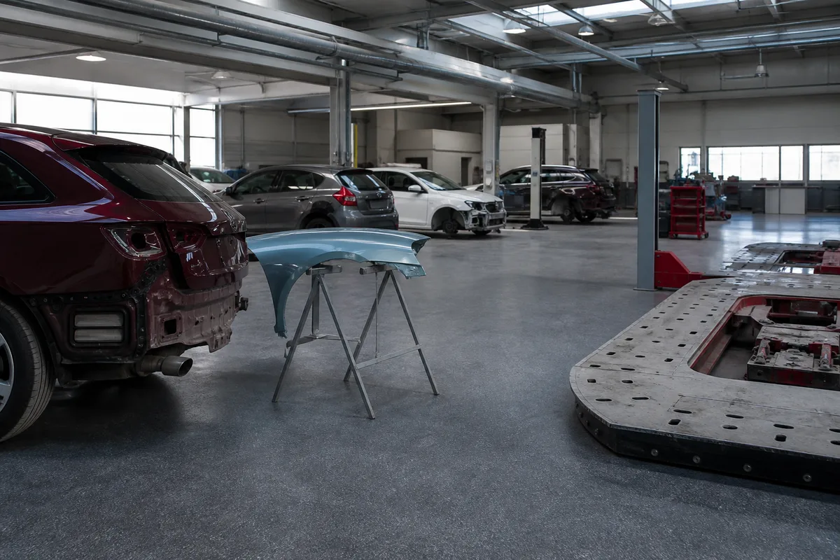 Vue d&rsquo;ensemble d&rsquo;un atelier de carrosserie avec plusieurs véhicules en attente de réparation