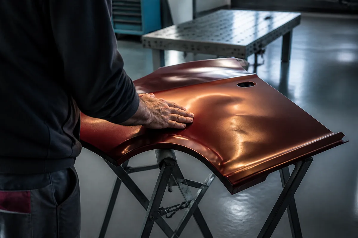Carrossier palpant une aile enfoncée à la lumière rasante pour évaluer la déformation
